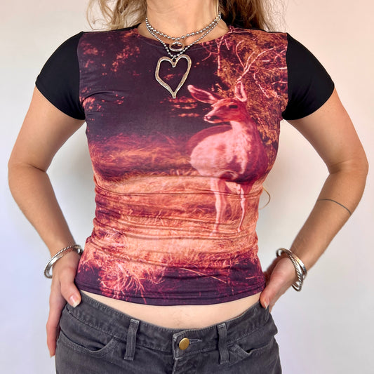 Person wearing a black t-shirt with a deer design and heart pendant necklace.